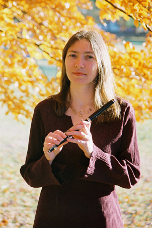 Sally Quantrill holding her flute in a park.